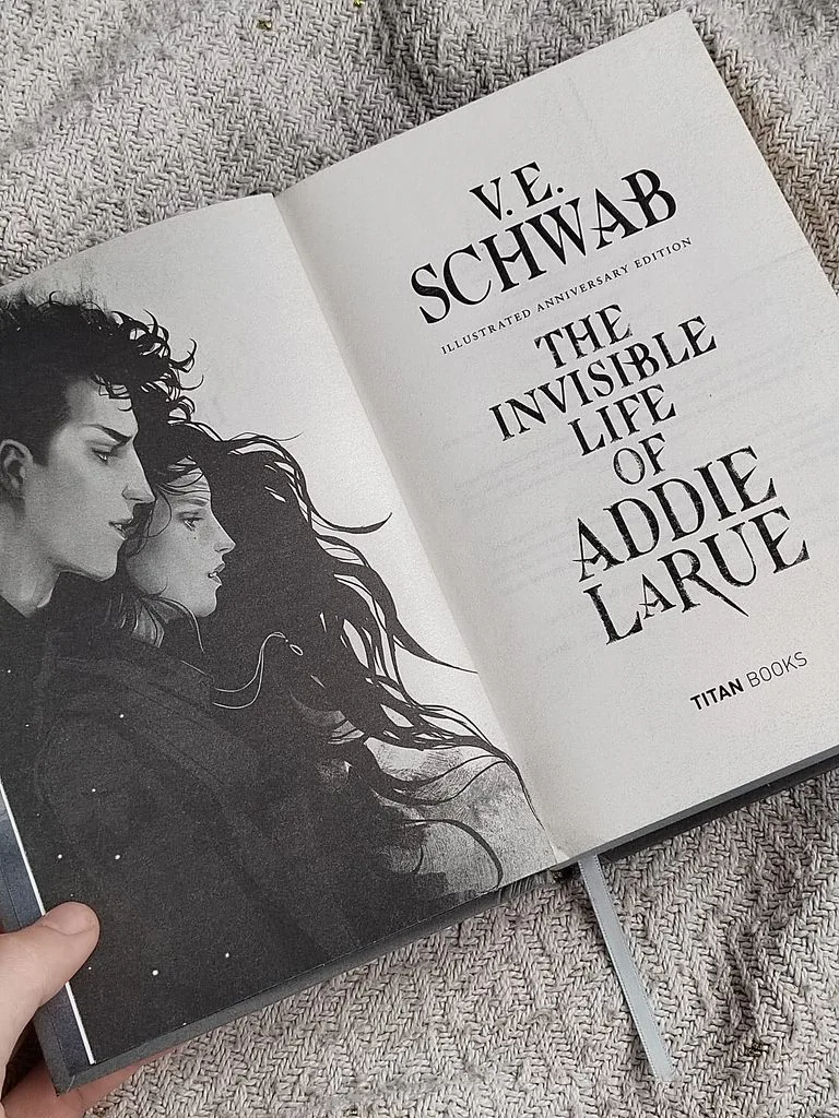 A photo of The Invisible Life of Addie LaRue open and showing the title page and the illustration of Addie and Luc together