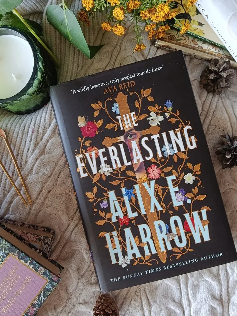 A photo of the hardback edition of The Everlasting by Alix E. Harrow against a blanket